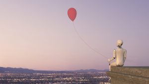 A white robot is sitting on the rooftop ledge of a building with the view of a city with lights, holding a red balloon.